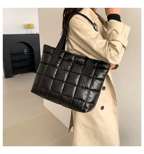 Close-up of black quilted down-style tote bag in glossy nylon with square stitching texture