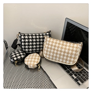 Detail of houndstooth crescent shoulder bag and mini round purse set on desk