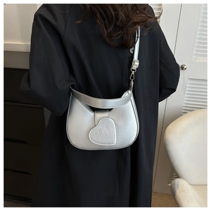 Detail of silver crescent shoulder bag featuring heart flap and LOVE embossed texture