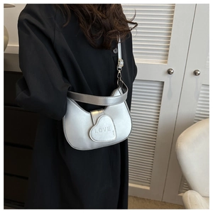 Detail of silver heart-shaped bag with LOVE embossing on metallic PU leather