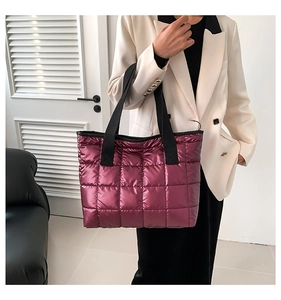 Detail of burgundy quilted tote bag with metallic finish and wide black nylon straps