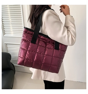 Detailed view of large quilted tote bag in burgundy metallic finish with wide black strap