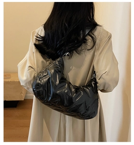 Vue arrière d'un grand sac matelassé noir brillant porté avec un trench-coat beige