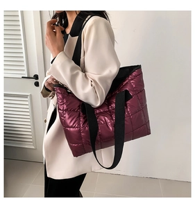 Detail of purple metallic quilted tote bag featuring wide black fabric shoulder straps