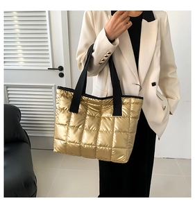 Close-up of quilted gold metallic tote bag with black fabric shoulder straps