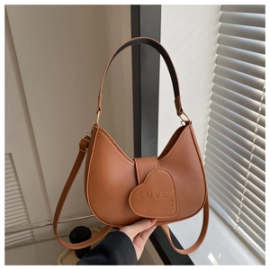 Detail of caramel brown half-moon bag featuring a love heart buckle with soft matte texture