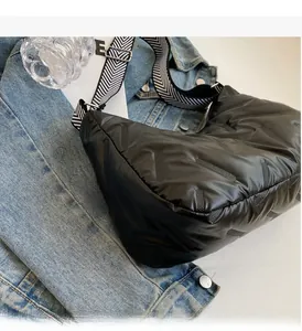 Détail du sac matelassé noir avec bandoulière à chevrons sur une veste en jean