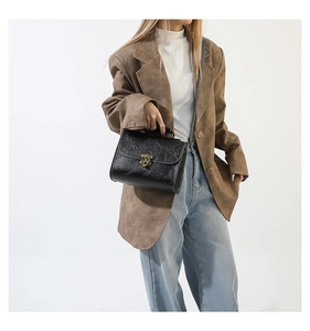 Detail of vintage black handbag featuring floral relief and bronze metal twist lock