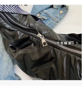 Détail de la fermeture éclair en métal argenté sur un sac bandoulière matelassé noir