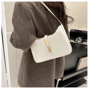 Close-up of white glossy hobo bag with gold metal buckle worn with a brown blazer