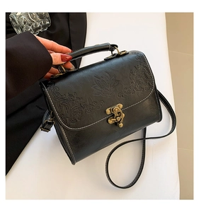 Detail of vintage embossed faux leather bag with bronze lock and floral pattern