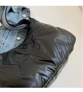 Détail du sac bandoulière noir matelassé avec une sangle en toile noire et blanche
