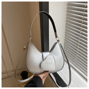 Close-up of silver crescent handbag with heart detail and LOVE embossed texture