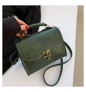 Close-up of vintage dark green crossbody bag with embossed floral pattern and bronze clasp