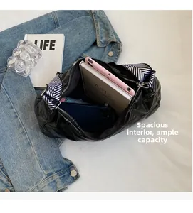 Intérieur spacieux du sac matelassé noir avec large bandoulière et objets du quotidien