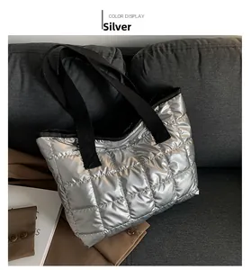 Detail of silver quilted tote bag featuring metallic finish and black woven strap