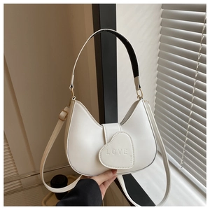Close-up of white heart-shaped saddle bag with LOVE embossing and gold hardware