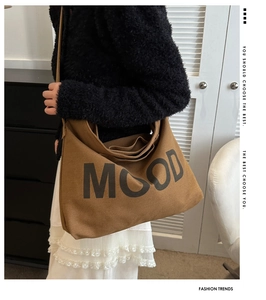 Détail du grand sac bandoulière en toile avec texte MOOD porté par un mannequin