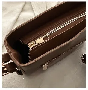 Dettaglio della cerniera dorata e della texture in pelle marrone opaca della borsa