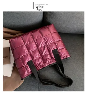 Detail of wine red quilted tote bag with padded texture and black ribbon handles