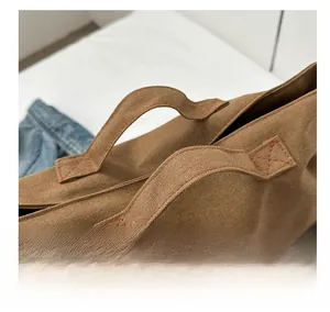 Détails des poignées renforcées d'un sac cabas en toile marron avec coutures solides