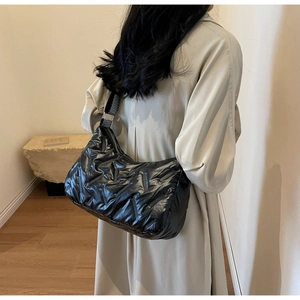 Détail d'un sac bandoulière matelassé noir brillant avec sangle à chevrons réglable
