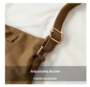 Détail de la boucle réglable en or rose sur la bandoulière en toile marron