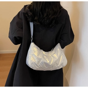 Détail du sac matelassé argenté avec une large bandoulière à motifs géométriques
