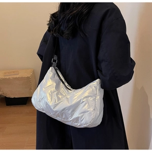 Détail d'un sac bandoulière argenté matelassé brillant avec bandoulière tissée sur le modèle