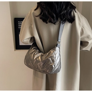 Détail du sac matelassé argenté avec une bandoulière tissée noire et blanche chic