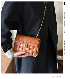 Detail of orange quilted leather texture with gold metal chain and square twist lock