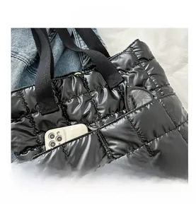Detail of black quilted puffer tote bag with front pockets for phone and glasses storage