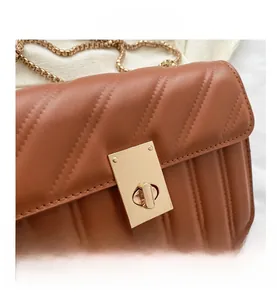 Close-up of brown quilted faux leather bag featuring a golden twist lock and chain strap