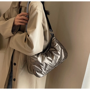 Détail du sac matelassé argenté avec bandoulière géométrique sur un mannequin en manteau beige
