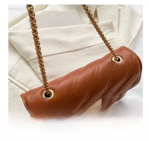 Detail of brown quilted faux leather bag with V-shaped stitching and gold chain strap