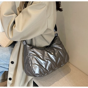 Détail du sac matelassé argenté montrant la texture métallique et la bandoulière rayée