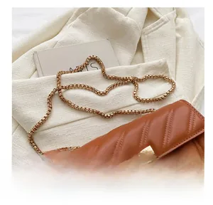 Close-up of brown quilted bag featuring golden chain strap and vintage twist lock