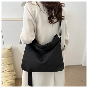 Vue latérale d'un grand sac cabas en toile noire avec bandoulière réglable sur un modèle
