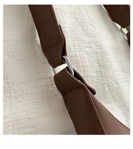 Detailed close-up of dark brown leather strap with metal ring buckle and fine stitching