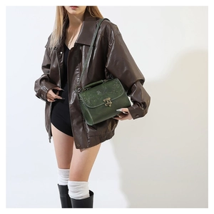 Vintage green embossed leather crossbody bag with bronze clasp shown on a model