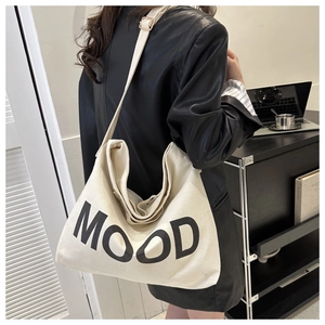 Détail d'un grand sac fourre-tout en toile crème avec lettrage MOOD et bandoulière