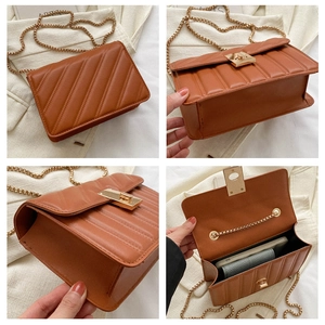 Detailed close-up of brown quilted crossbody bag with gold rotating lock and chain strap