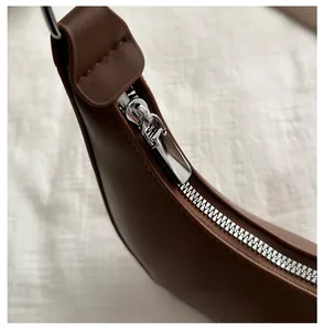 Detail of smooth silver zipper and premium brown leather texture on shoulder bag