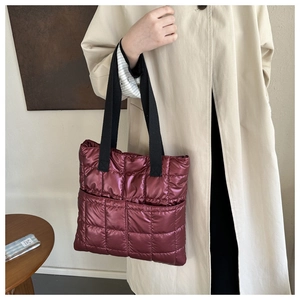 Close-up of wine red quilted down tote bag in shiny nylon with black straps