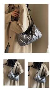 Détail du sac matelassé argenté brillant avec bandoulière noire et texture rembourrée