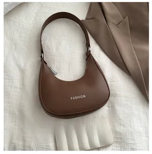 Flat lay of dark brown crescent hobo bag next to a mobile phone for size reference