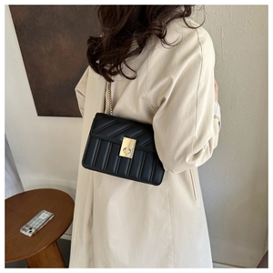 Close-up of a black quilted leather crossbody bag with a golden turn-lock and chain strap