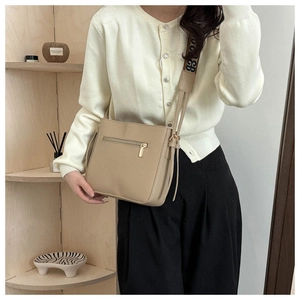 Dettaglio borsa a tracolla in pelle beige con ampia tracolla jacquard e tasca a zip