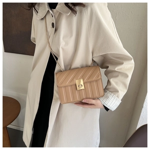 Detail of light brown quilted bag featuring gold metal chain strap and turn-lock closure