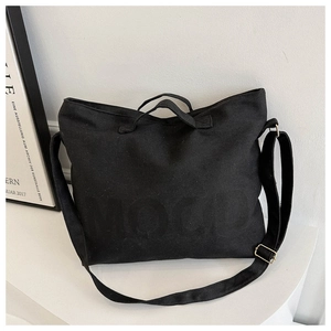 Détail du sac cabas en toile noire montrant le lettrage MOOD et les boucles en bronze